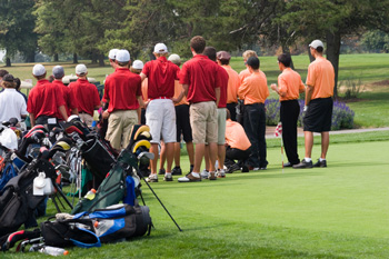 Group of golfers in red and in orange shirts at tournament 
